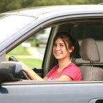 A young female in the driver side of a car representing a teen driver