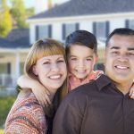 Family posing in front of their home after getting life insurance