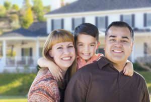 Family posing in front of their home after getting life insurance