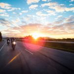 Motorcycle riders driving on a highway during sunset