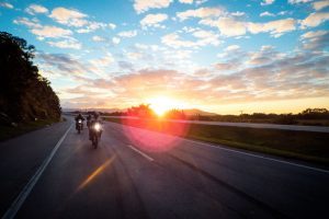 Motorcycle riders driving on a highway during sunset