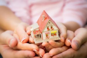 Pairs of hands holding up a model home