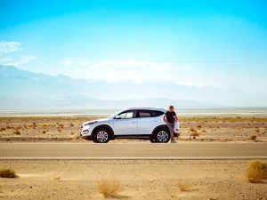 A person standing next to a car parked on the side of the road