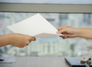 A person passing a piece of paper to another person