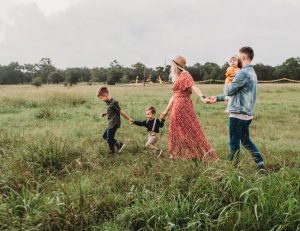 A family of five walking through a field of grass